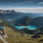 A hiker sits on top of a mountain overlooking a lake.